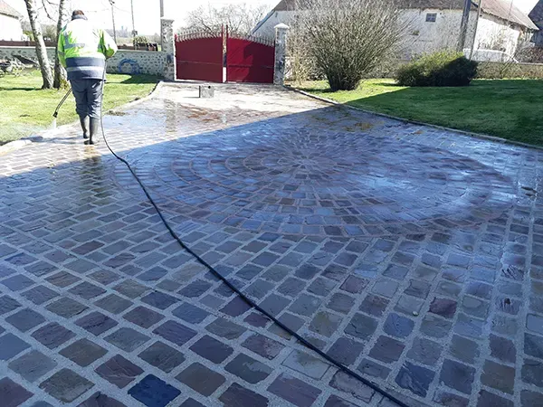 Personne nettoyant une allée pavée